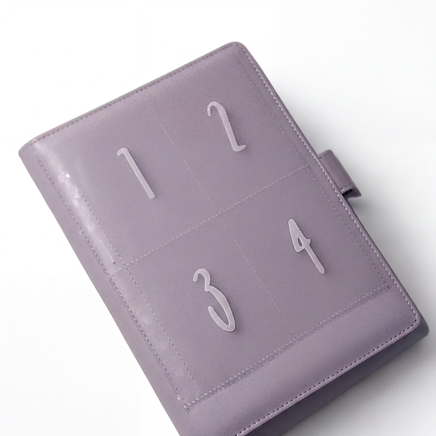 A purple leather-bound notebook or planner with numbered pages, including the numbers 1, 2, 3, and 4.