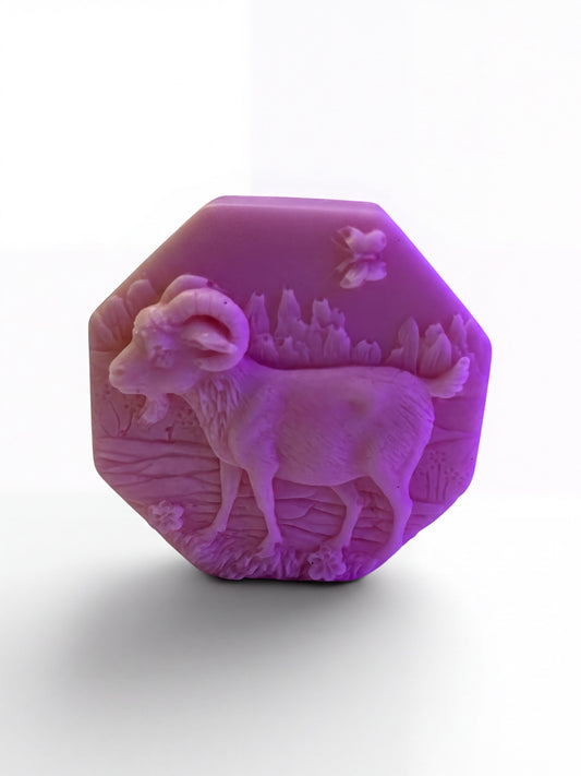 A pink soap dish with a goat design sits on a white countertop, accompanied by a rose, a vanilla stick, and a folded towel.
