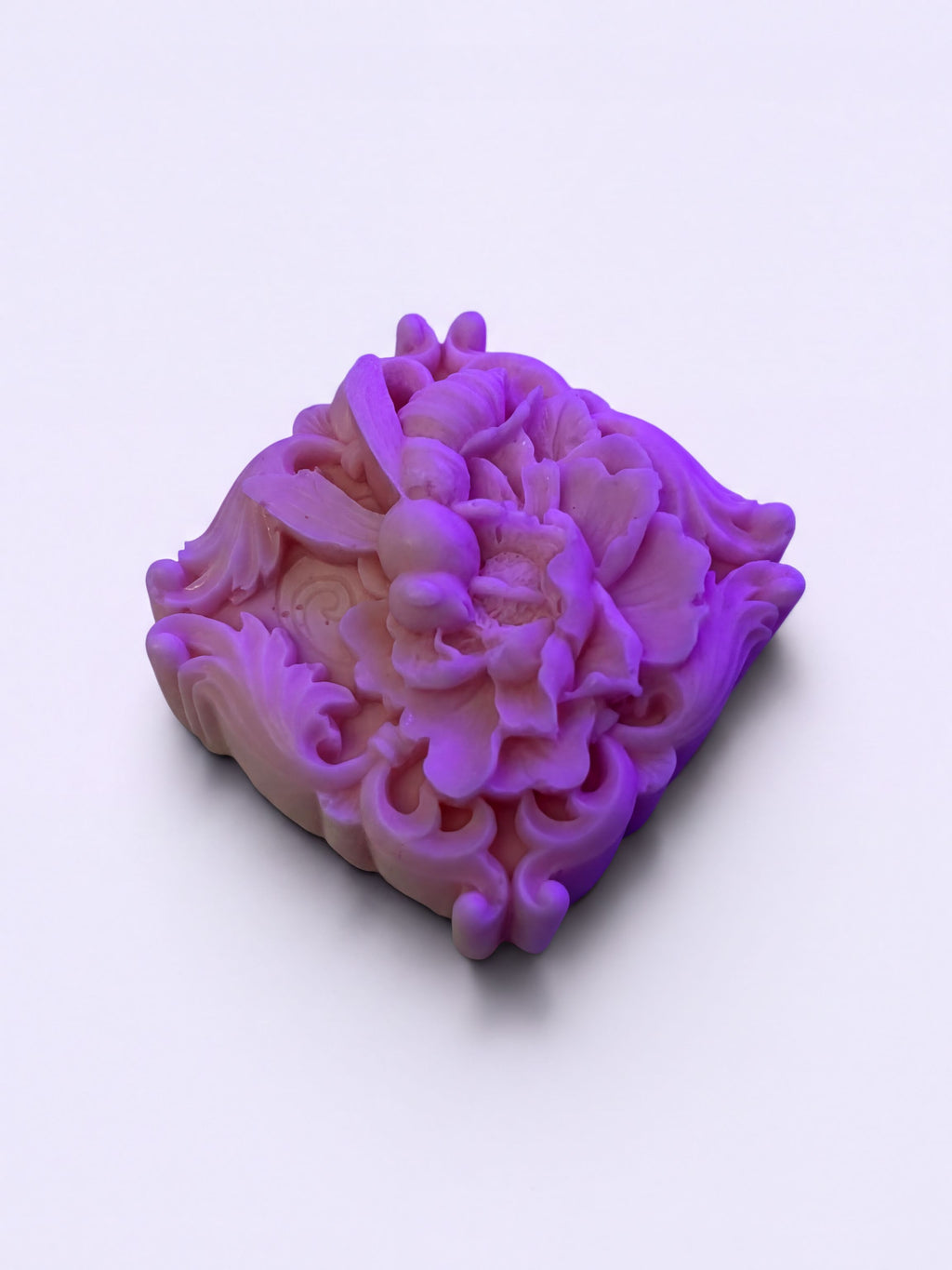 A square-shaped, purple soap with an intricate floral design on it.