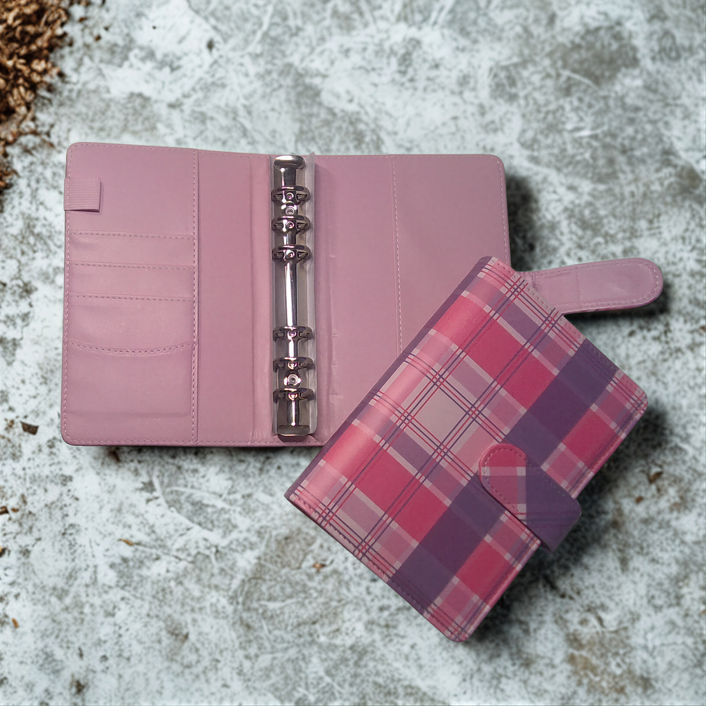 Pink plaid planner with ring binder and card slots on textured surface
