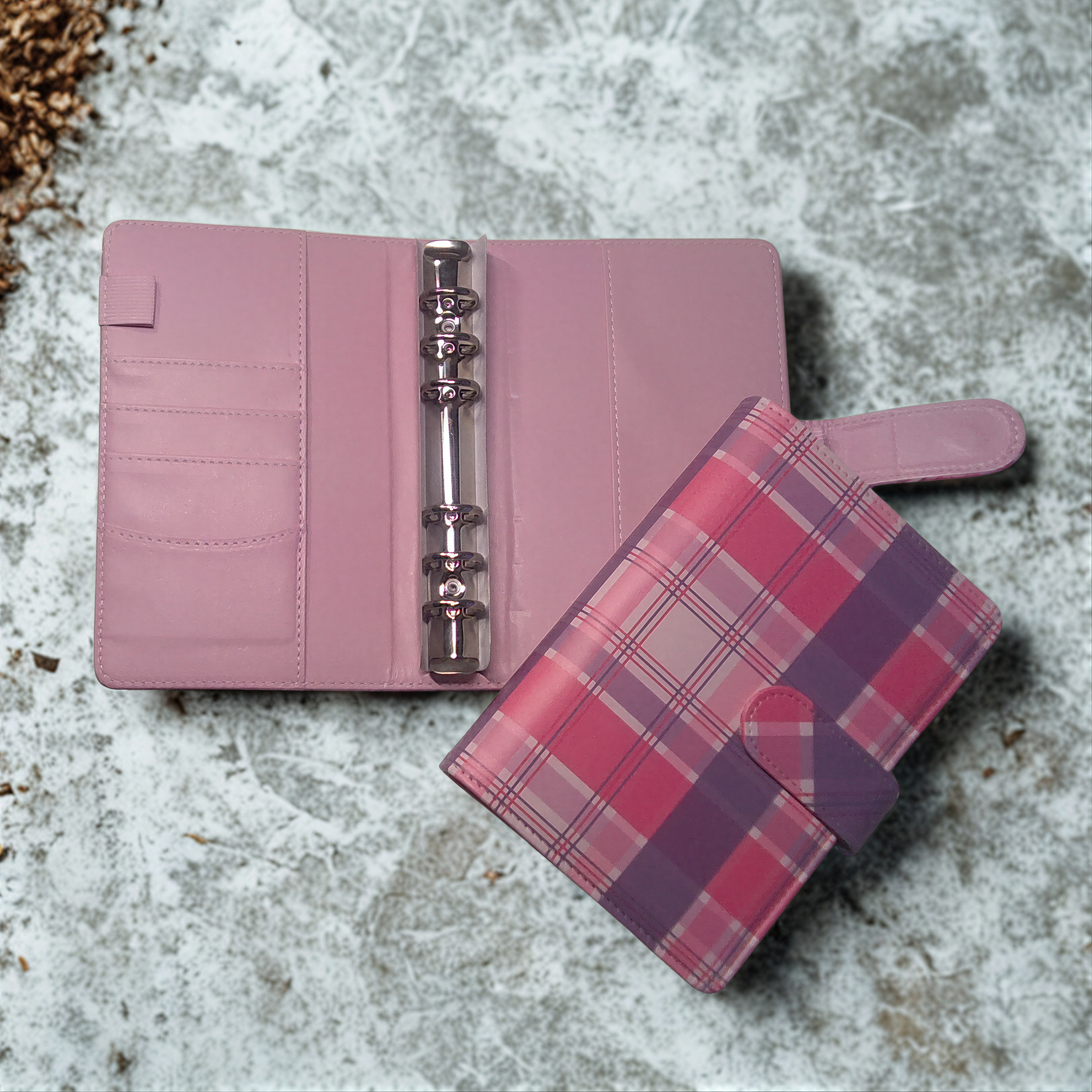 Pink plaid planner with ring binder and card slots on textured surface
