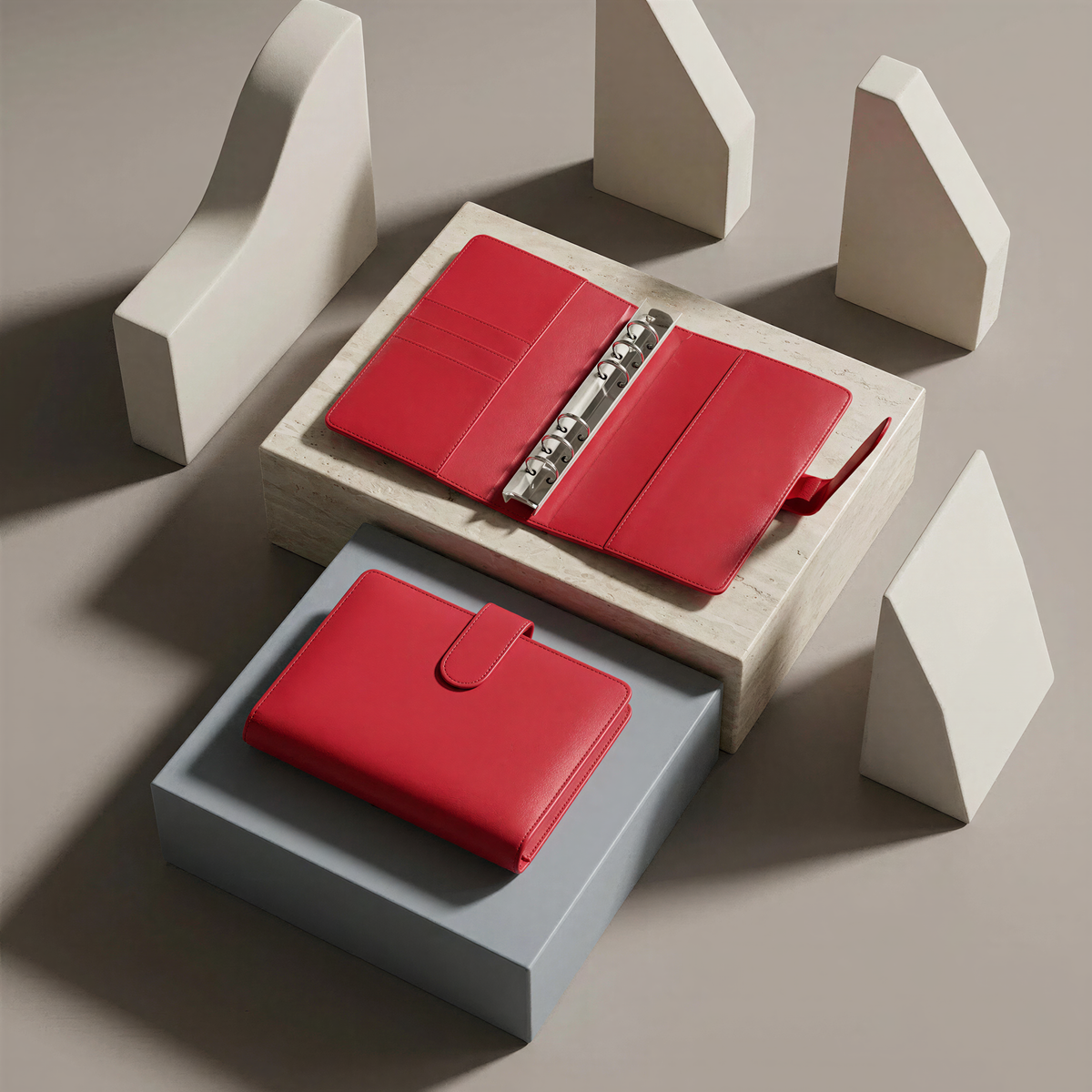 a red leather wallet and a red leather binder, both placed on a gray surface.