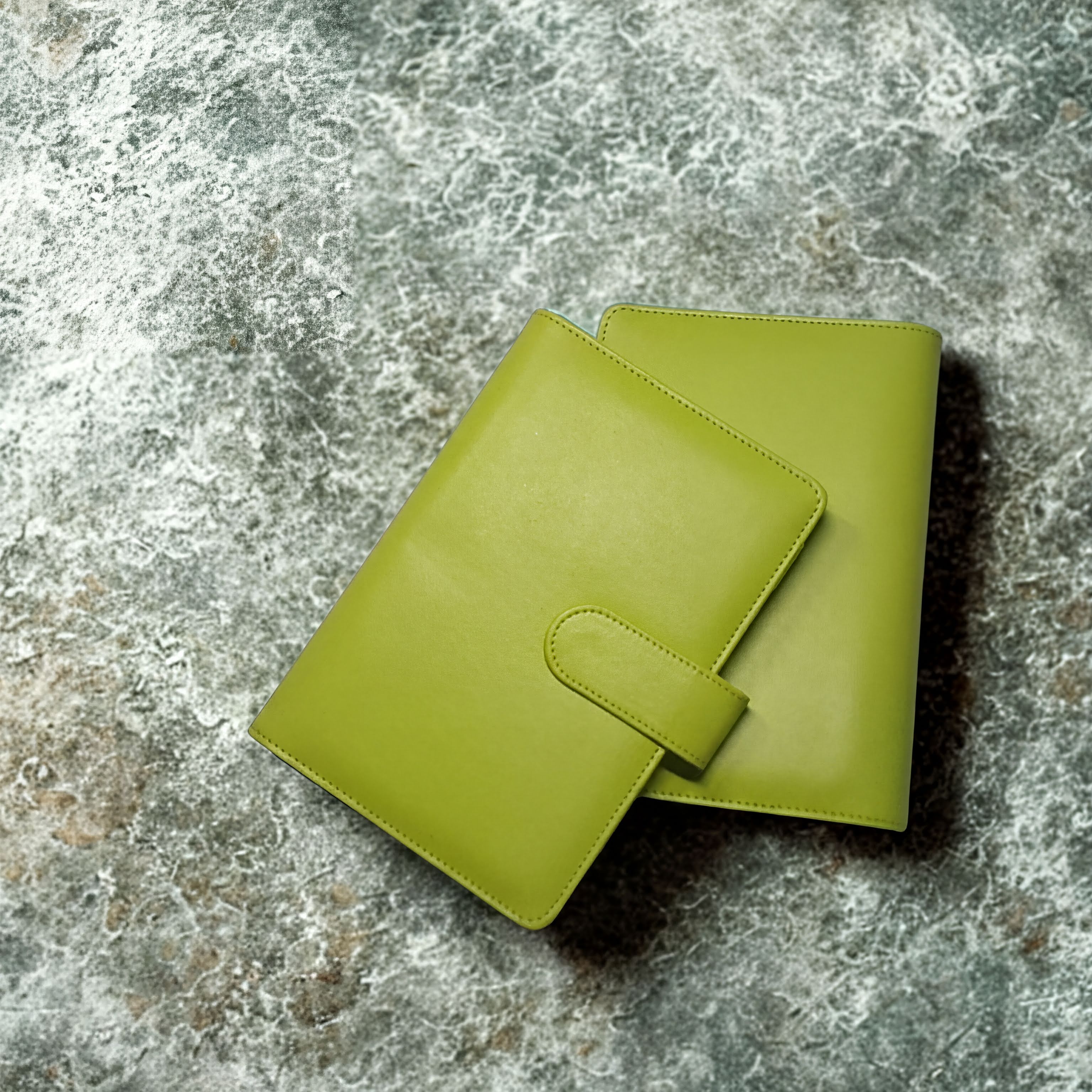 Lime green leather wallet with strap closure on textured stone surface