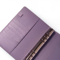 A purple leather-like notebook or binder with a metal ring attached, placed on a white surface.