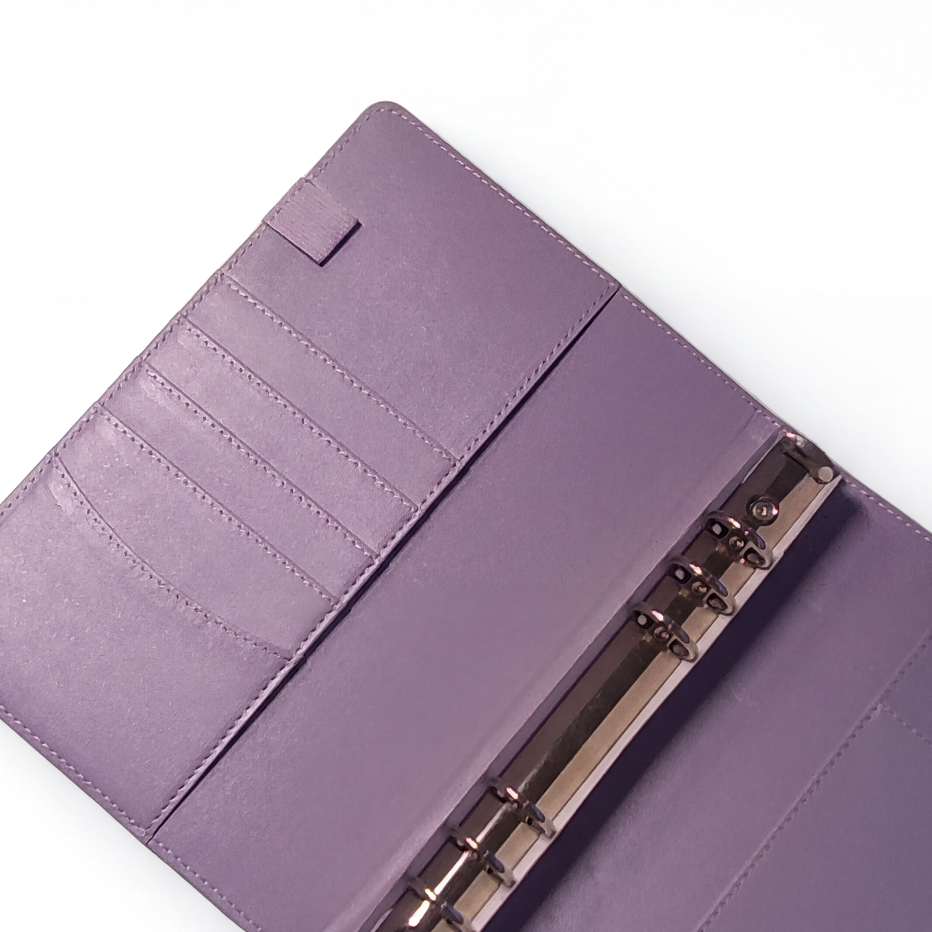 A purple leather-like notebook or binder with a metal ring attached, placed on a white surface.