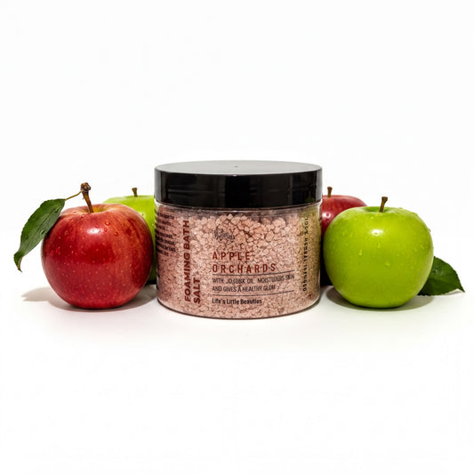 a jar of Apple Orchards Salt surrounded by three apples, with one green apple on the right side.