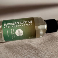 A bottle of Hawaiian sunscreen body oil spray is shown on a textured surface.
