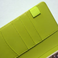 A close-up view of a bright green leather wallet or card holder with a zipper closure.