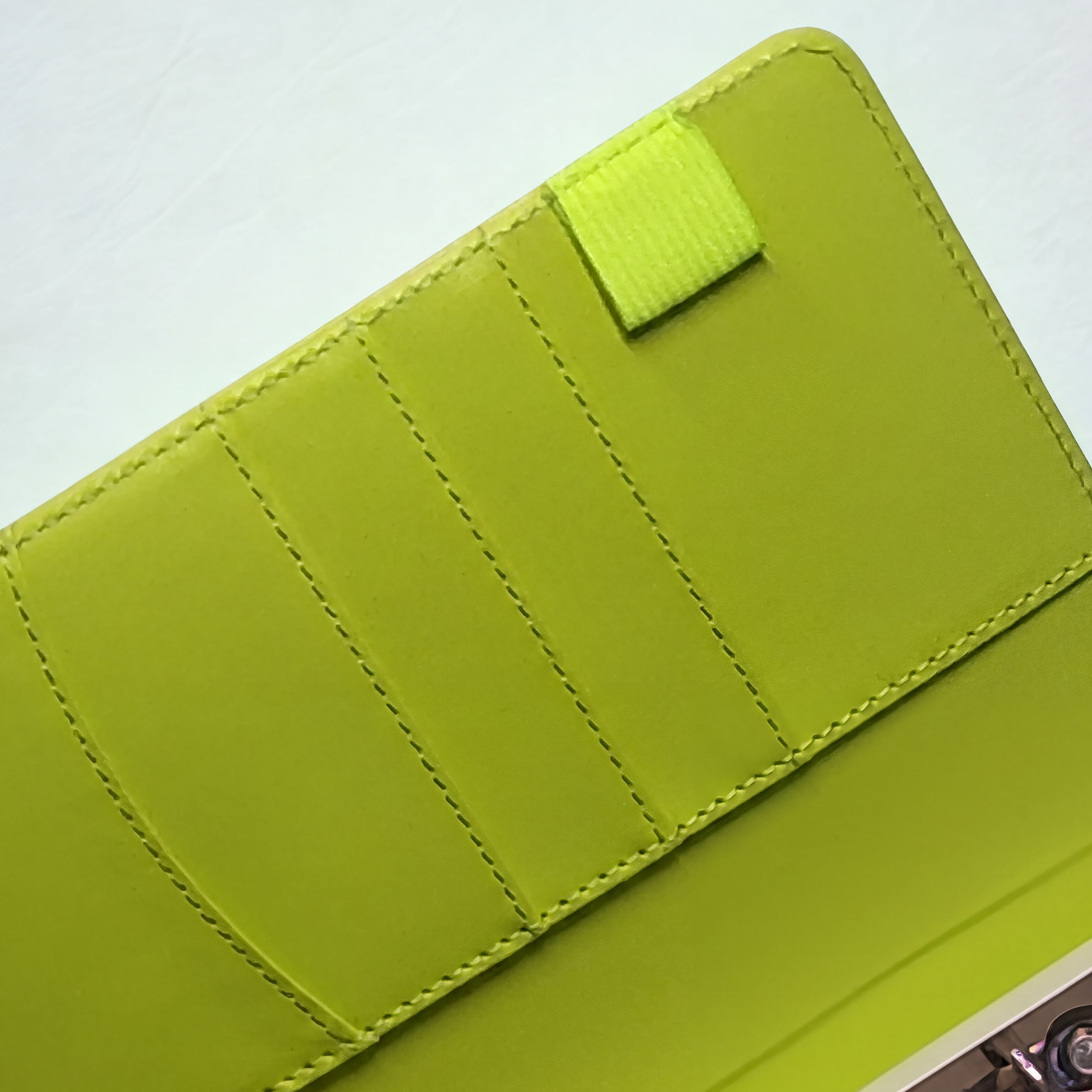 Lime green quilted wallet with velcro closure, featuring neat stitching and a vibrant, modern design.