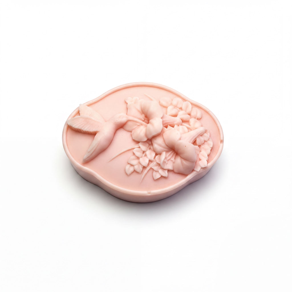 A pink soap with a bird and flower design on it.