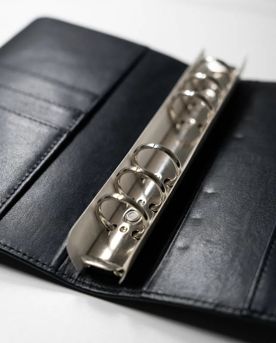 A black leather binder with a metal ring mechanism, which appears to be a binder or folder.