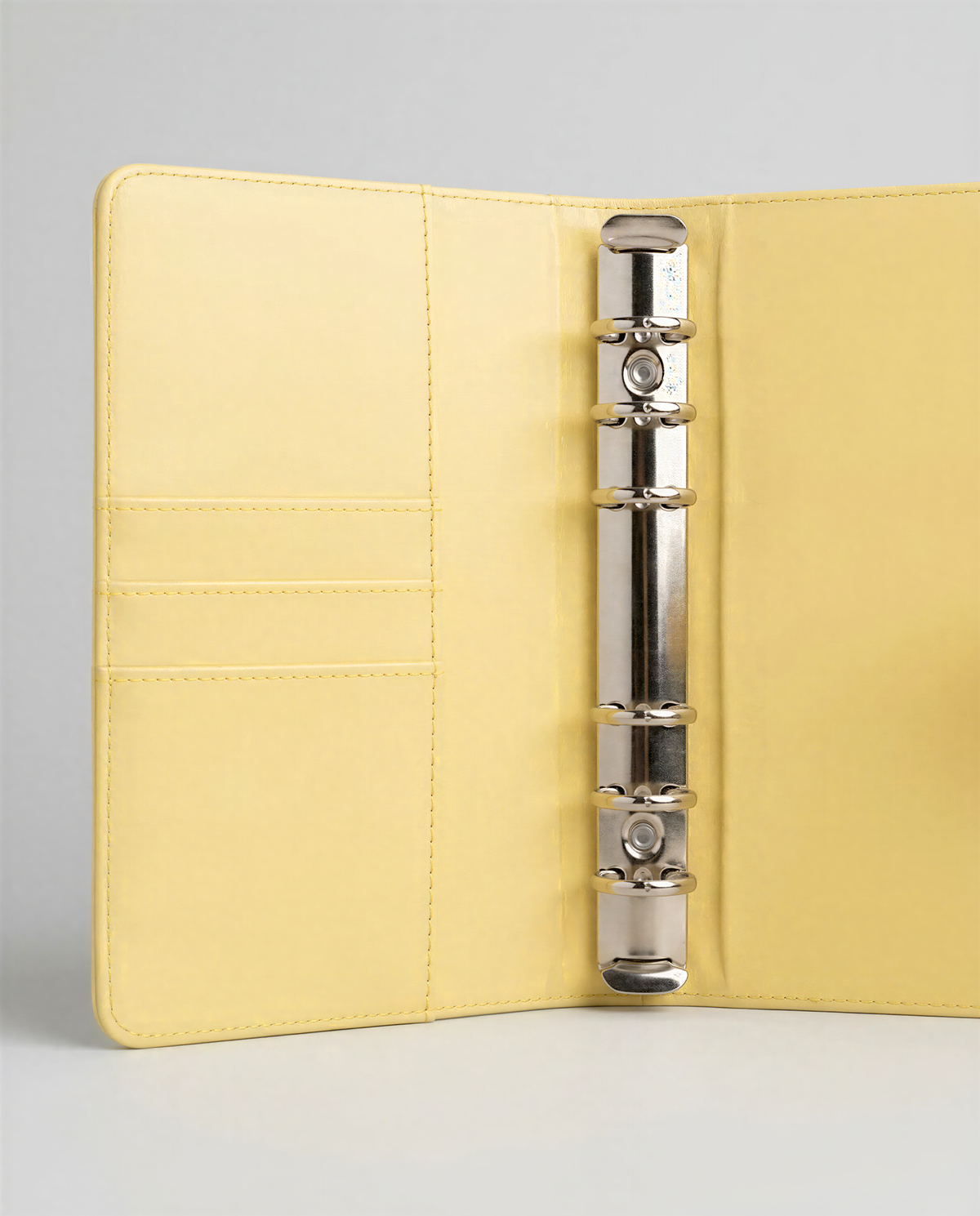 A yellow binder with a metal ring and pockets, placed on a white surface.