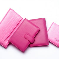 a collection of pink leather wallets and purses arranged on a white background.