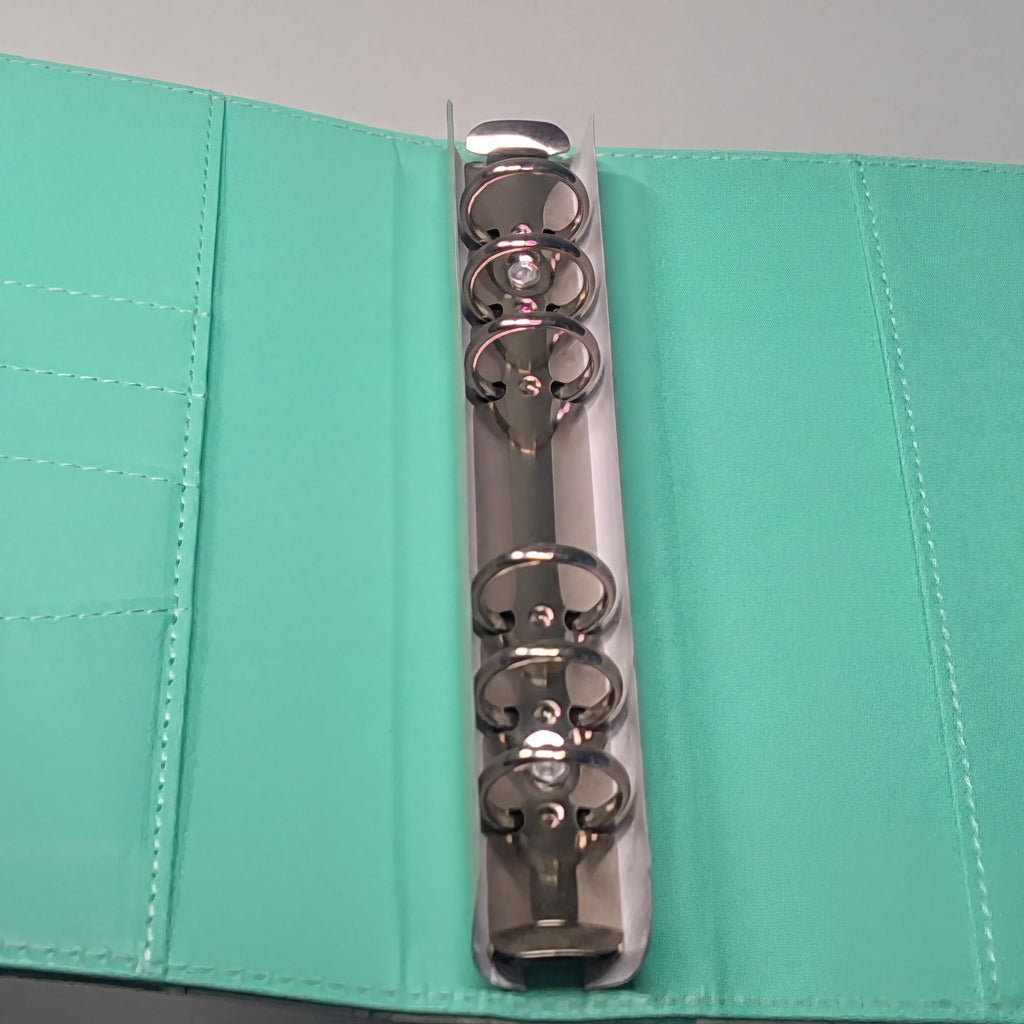 Mint green fabric planner with silver 6-ring binder mechanism, showcasing durable stitching and sleek metal hardware.