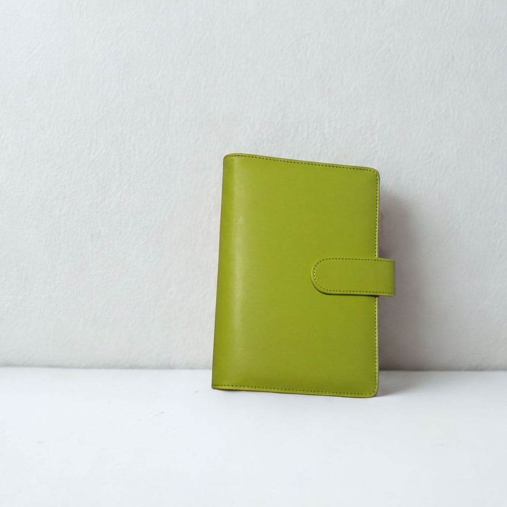 Lime green leather notebook with snap closure, minimalist design against white background