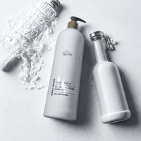 two white bottles of body wash, one larger and one smaller, placed on a white surface.