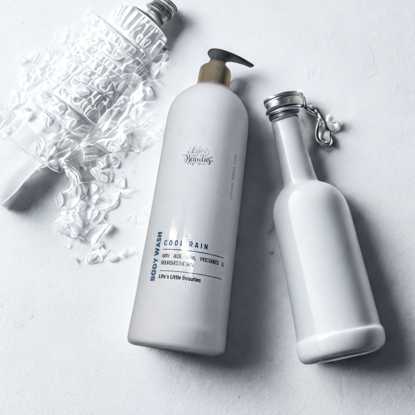 two white bottles of body wash, one larger and one smaller, placed on a white surface.