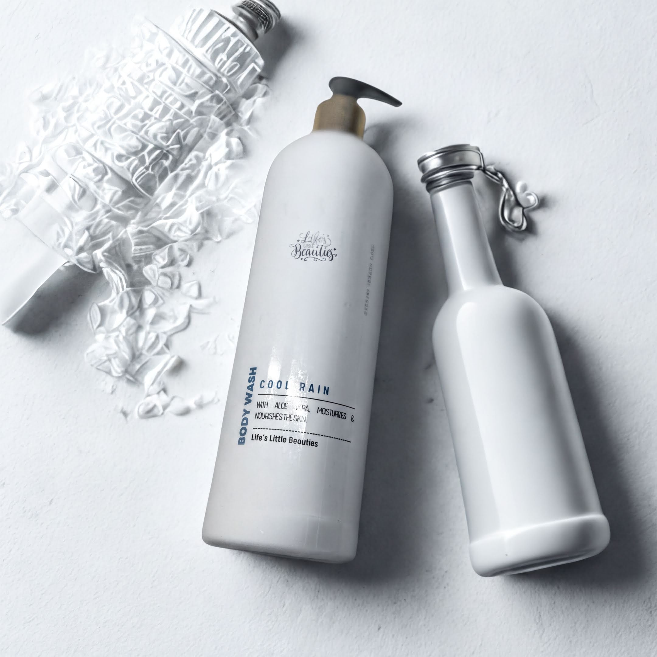 two white bottles of body wash, one larger and one smaller, placed on a white surface.