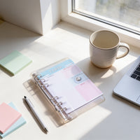 a desk with various items, including a notebook, a pen, a laptop, a mug, and some sticky notes.