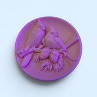 A purple ceramic plate with a detailed bird carving design on it.