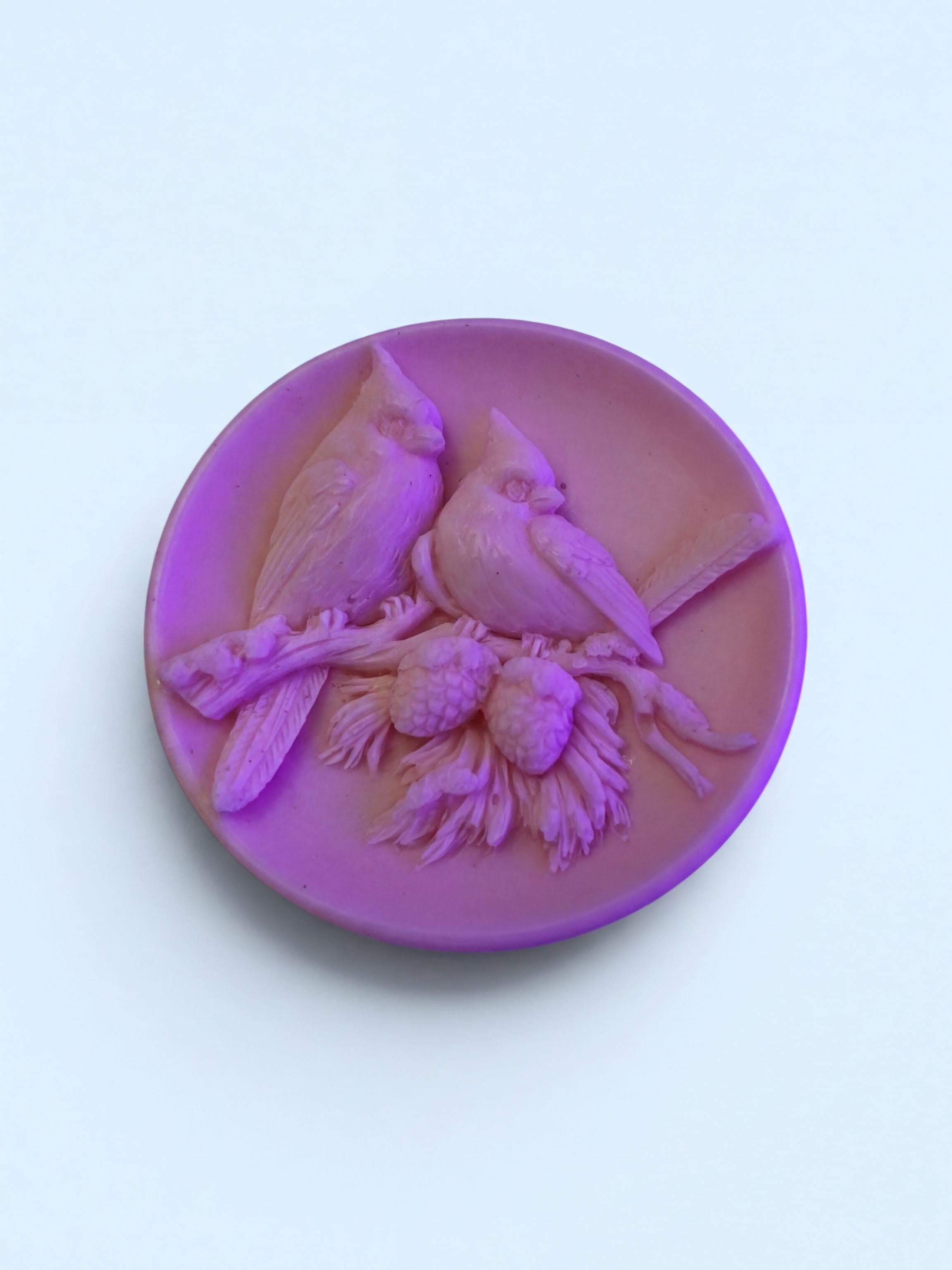 A purple ceramic plate with a detailed bird carving design on it.