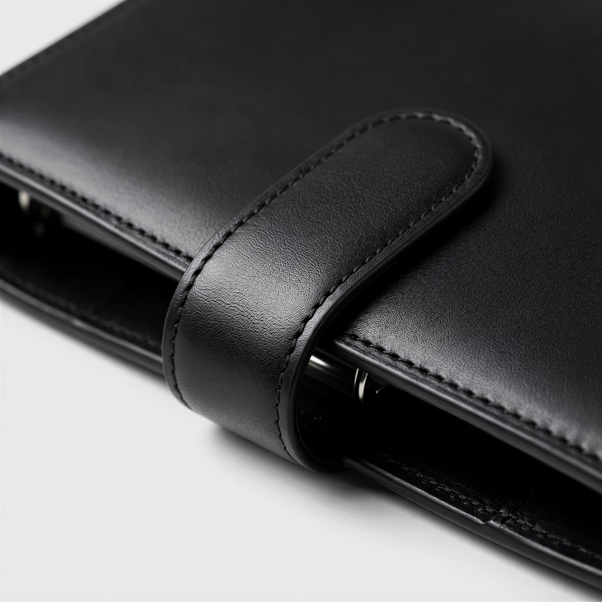 A close-up view of a black leather wallet or folder with a metal clasp.