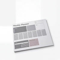a white weekly planner with a calendar and a list of daily goals.