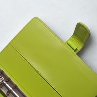 A bright green leather binder or folder with a metal ring cover.