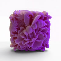 A purple, intricately carved soap sculpture depicting a bee.
