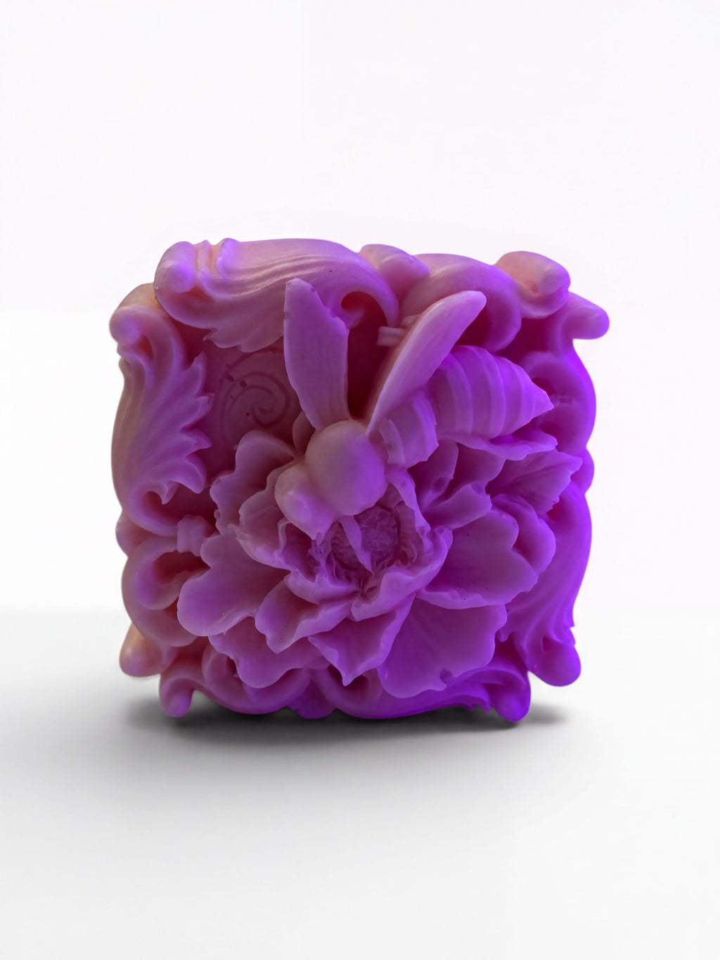 A purple, intricately carved soap sculpture depicting a bee.