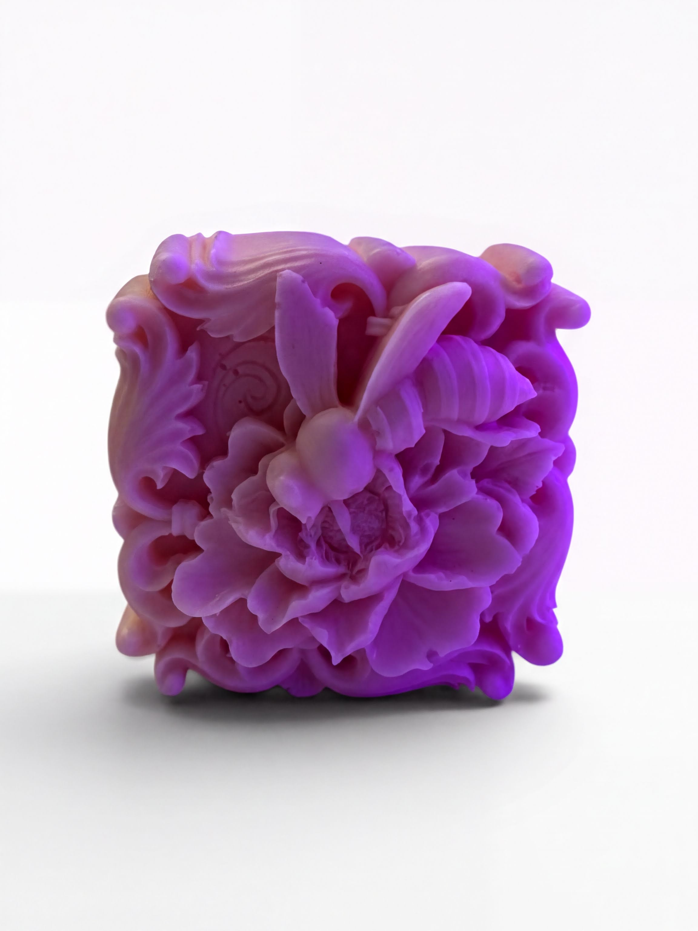 A purple, intricately carved soap sculpture depicting a bee.