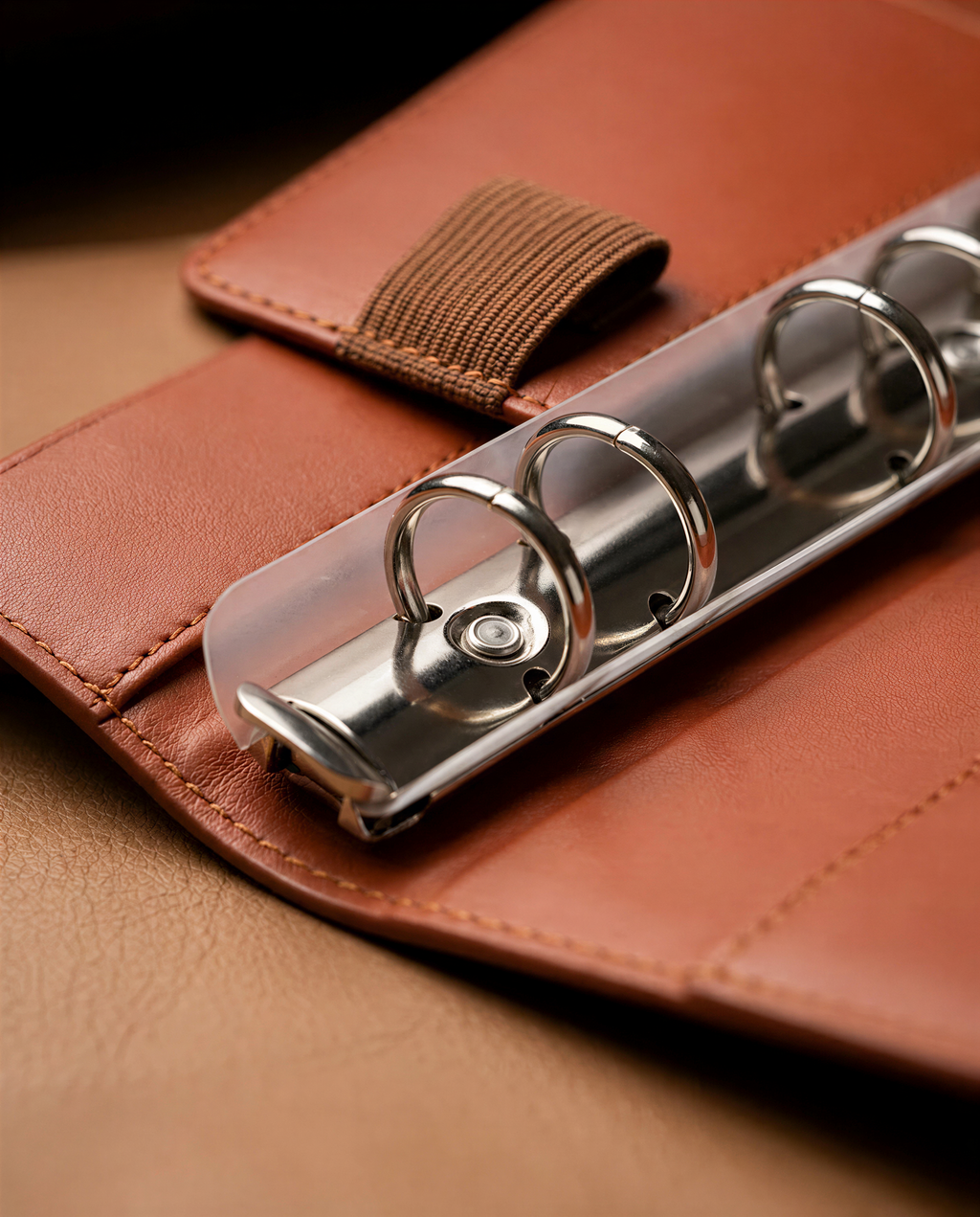 A close-up image of a leather binder with metal rings, resting on a leather surface.