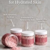 three jars of pink bath salt with white lids, arranged on a marble surface. The jars are labeled as "Formulated to Hydrate the Skin" and are described as "Rich, luxurious, foaming" and "Special Offer Now $15".