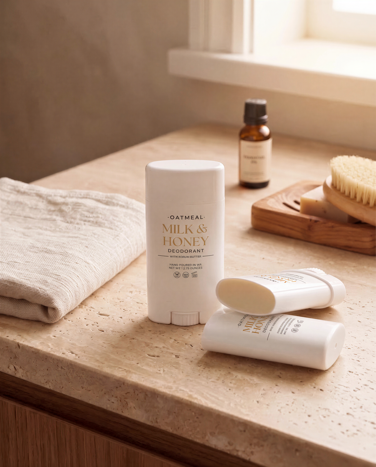 a bathroom countertop with various personal care items, including a bottle of Milk & Honey Deodorant, a bottle of Milk & Honey Body Oil, and a brush.