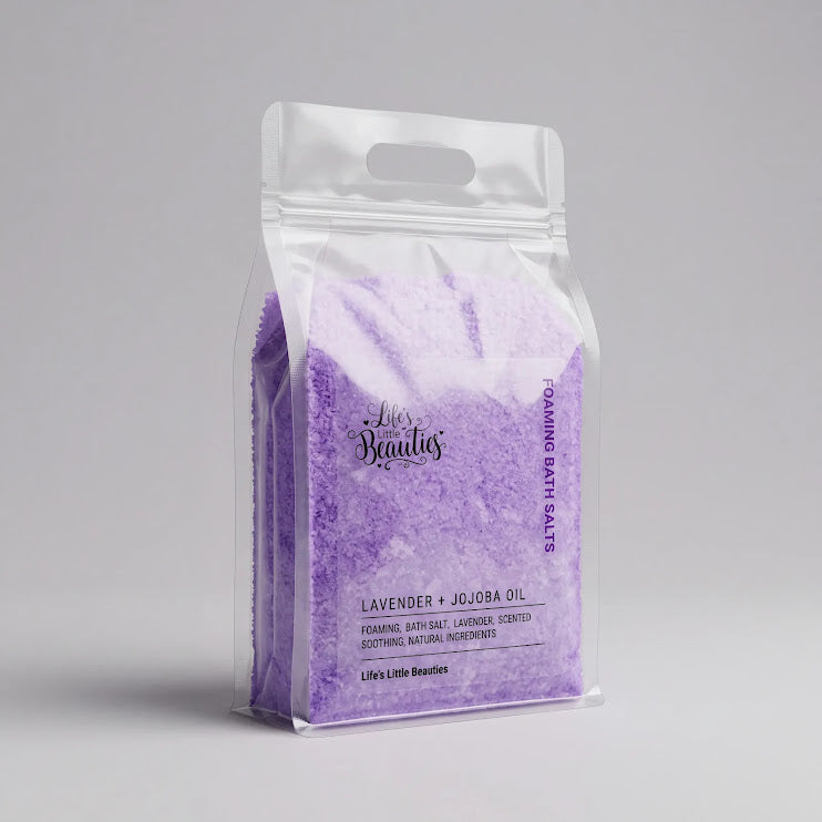A clear plastic bag filled with lavender-colored bath salt, labeled as a "Lavender + Jojoba Oil" product.