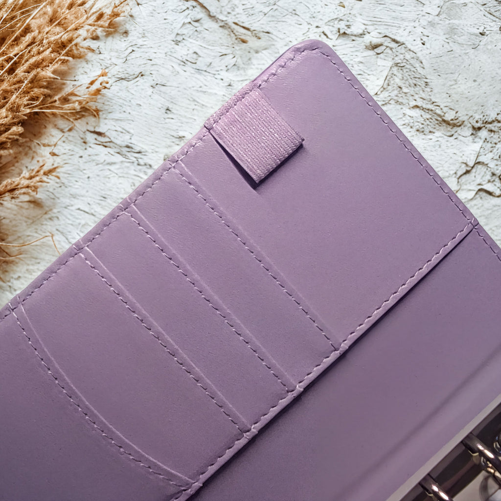 Lavender purple planner cover with stitched detailing and velcro closure on textured background