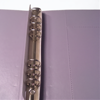 A silver metal ring is attached to a purple folder, with the ring's teeth visible.