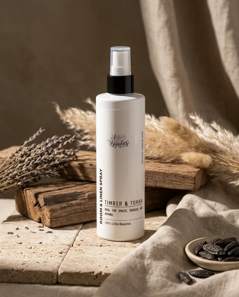 a bottle of "Lets Lendlin's" room and linen spray placed on a wooden surface, surrounded by dried lavender and pampas grass.