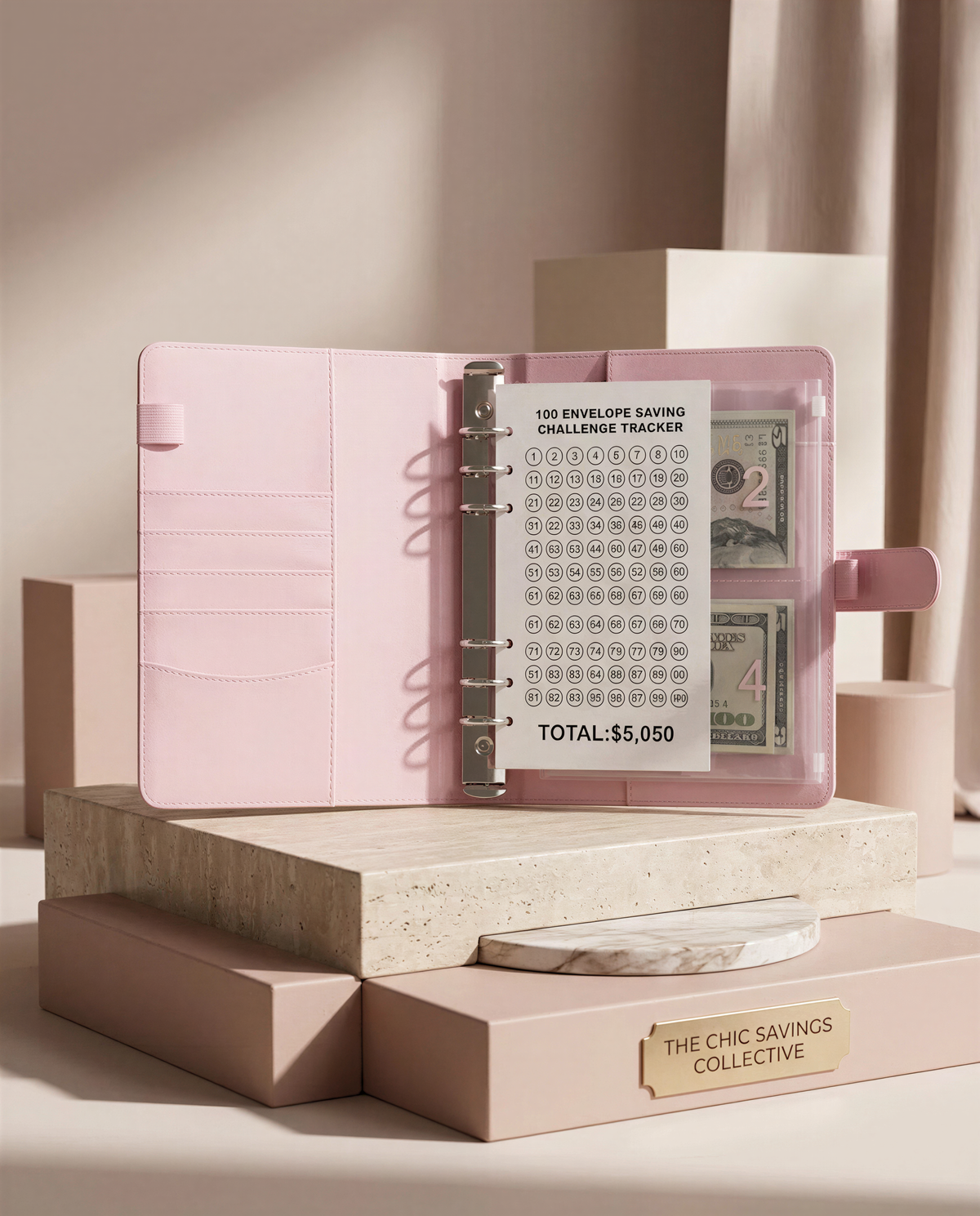 A pink organizer with a challenge tracking system for saving money, placed on a marble surface.