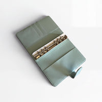 A mint green leather binder with a metal ring cover and a metal ring inside, placed on a white surface.