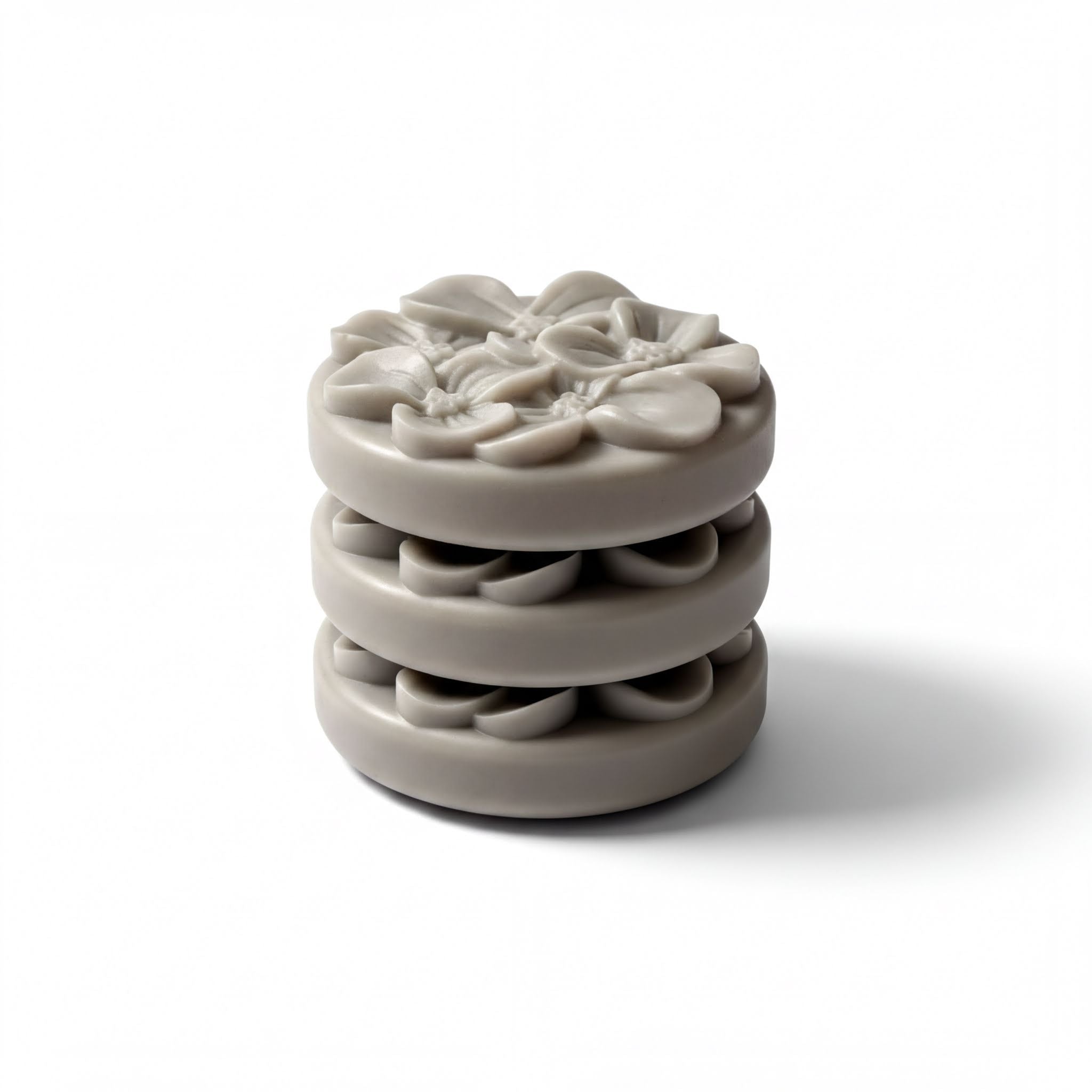 A stack of three gray, circular objects with a floral design on top.