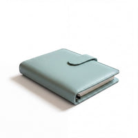 A light blue leather-bound notebook or binder with a metal clasp and a white cover.