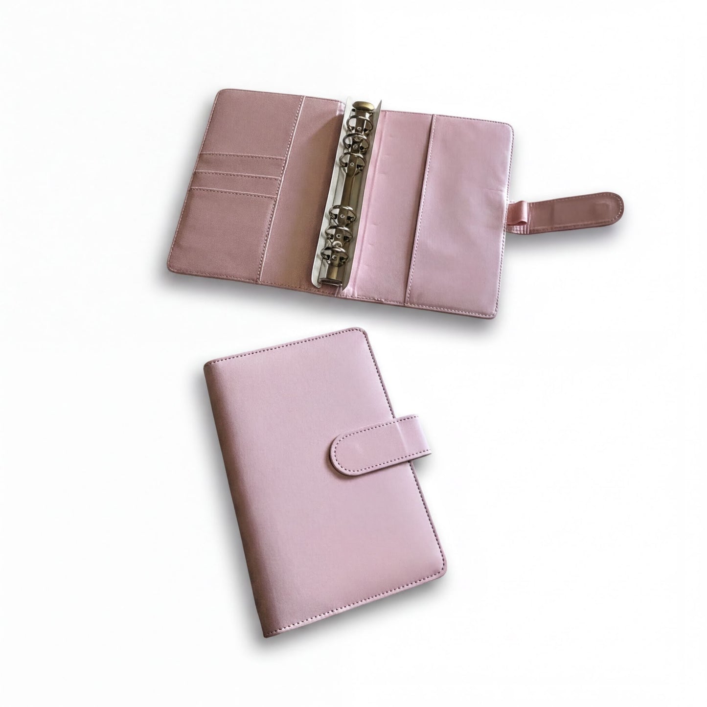 two pink leather-bound planners or notebooks with metal rings, one open and the other closed.