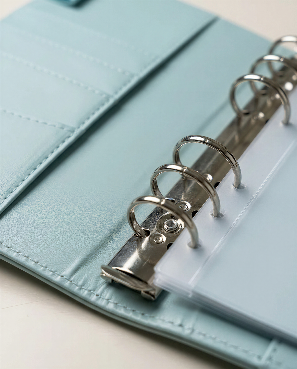 A light blue leather-like notebook with metal rings and a clear plastic cover.