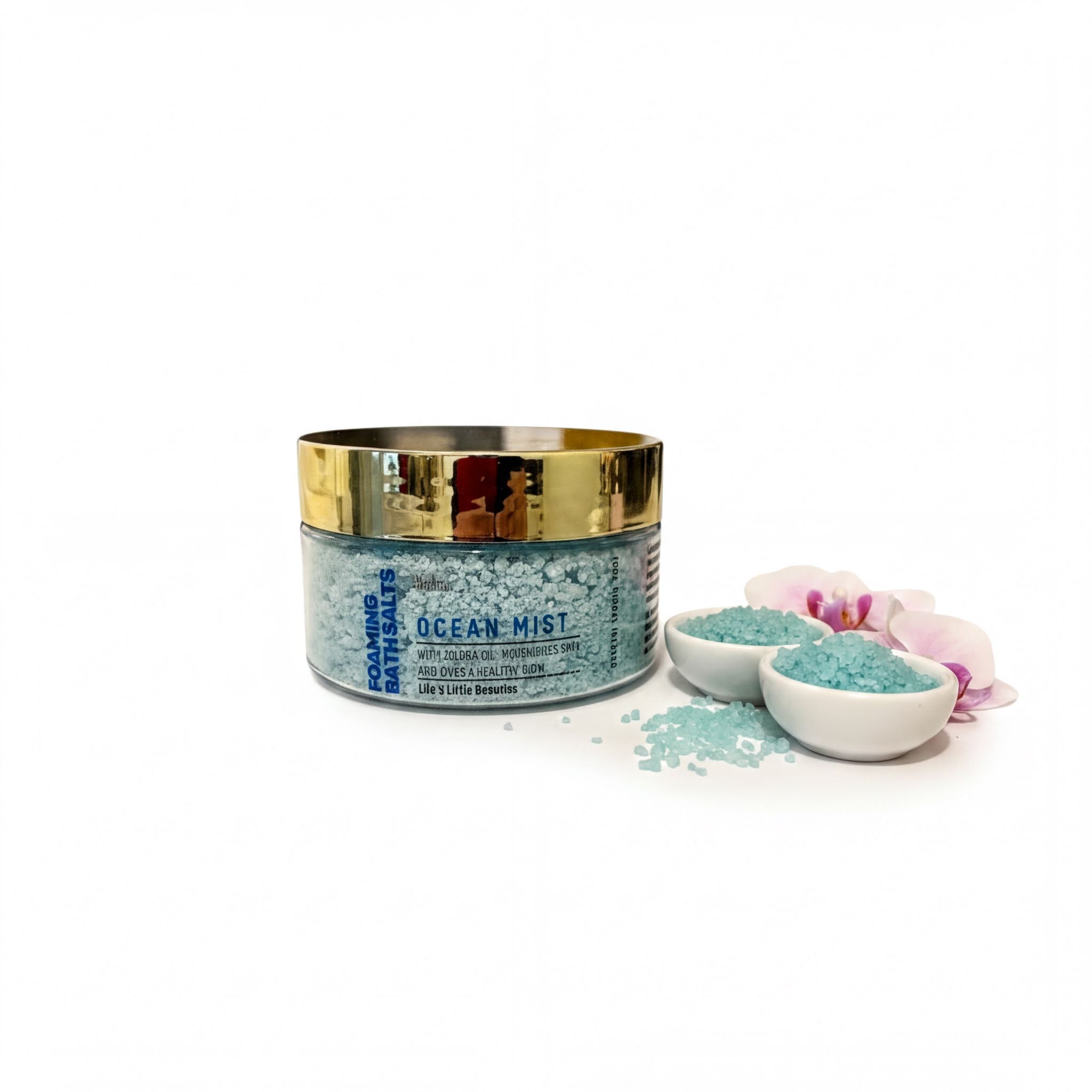 a jar of Ocean Mist bath salt with a gold lid, surrounded by small white bowls filled with the same blue-green bath salt, and a few pink orchid petals.