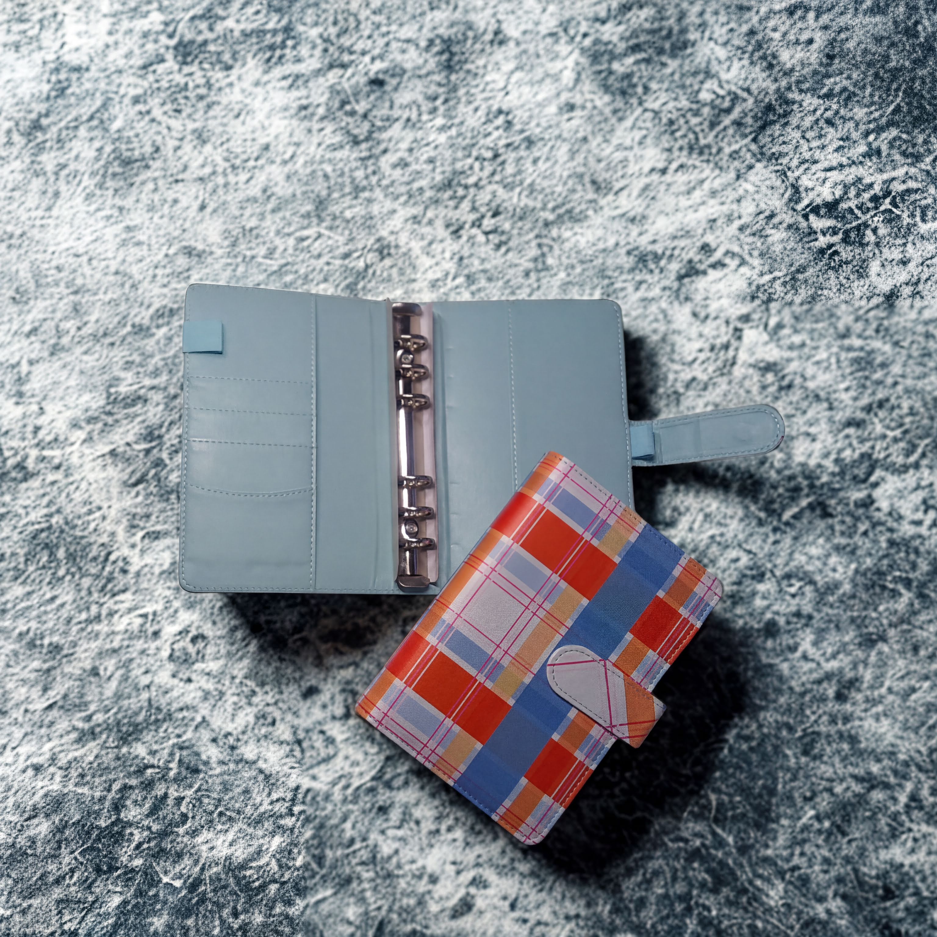 Light blue ring binder planner with plaid cover on textured surface