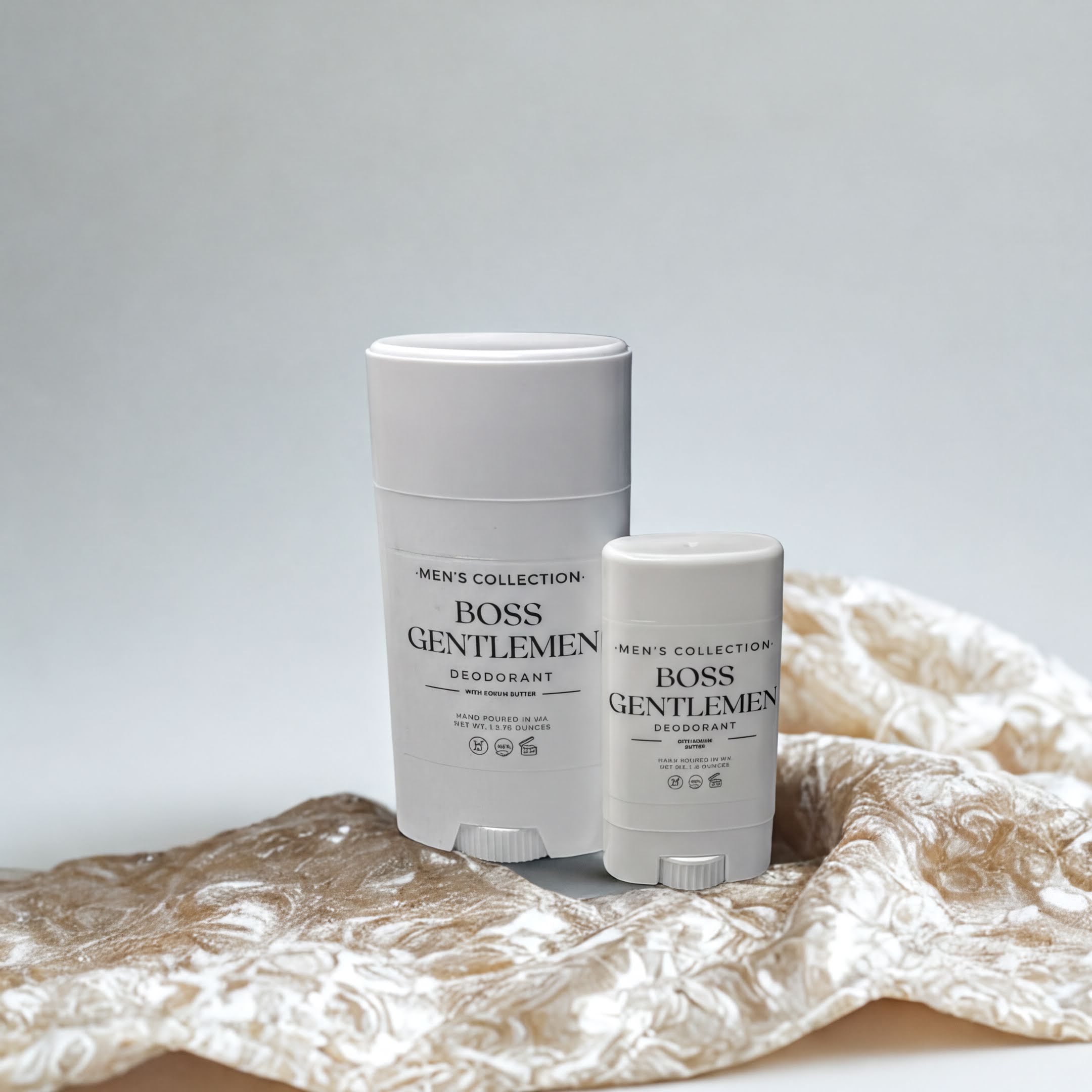 Two white deodorant sticks from the "Men's Collection" are placed on a beige fabric with a floral pattern.