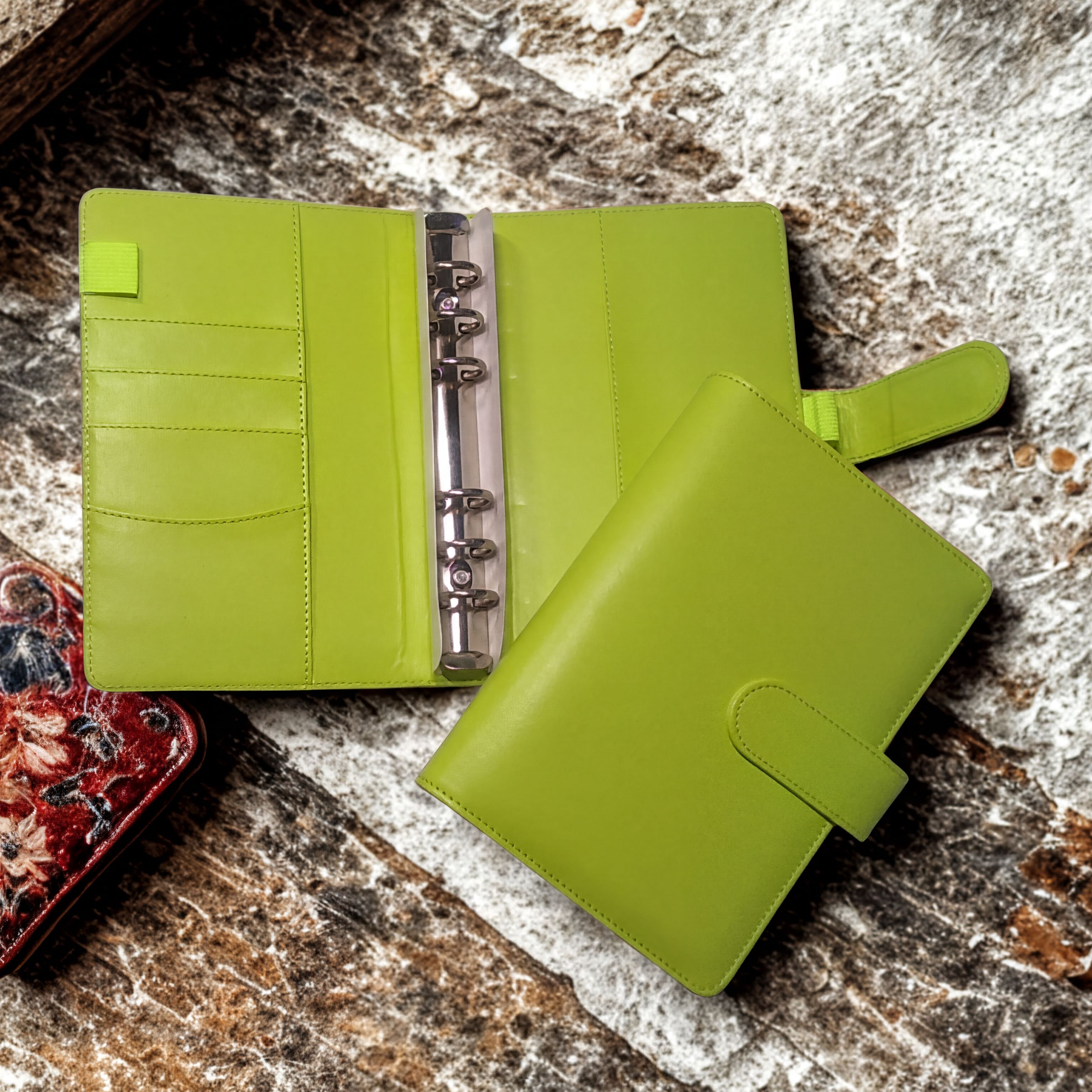 Lime green leather planner with ring binder and card slots on rustic stone surface