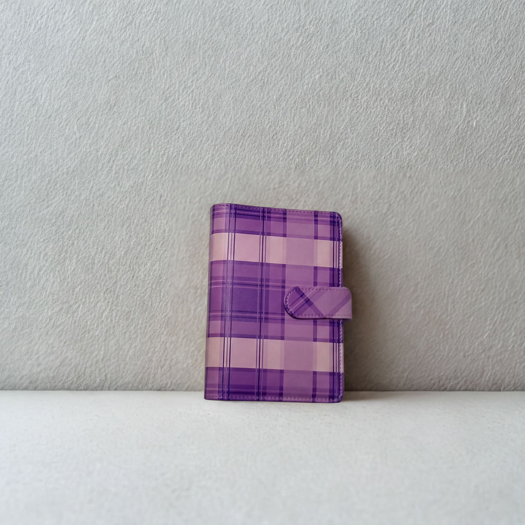Purple plaid notebook with snap closure on white surface