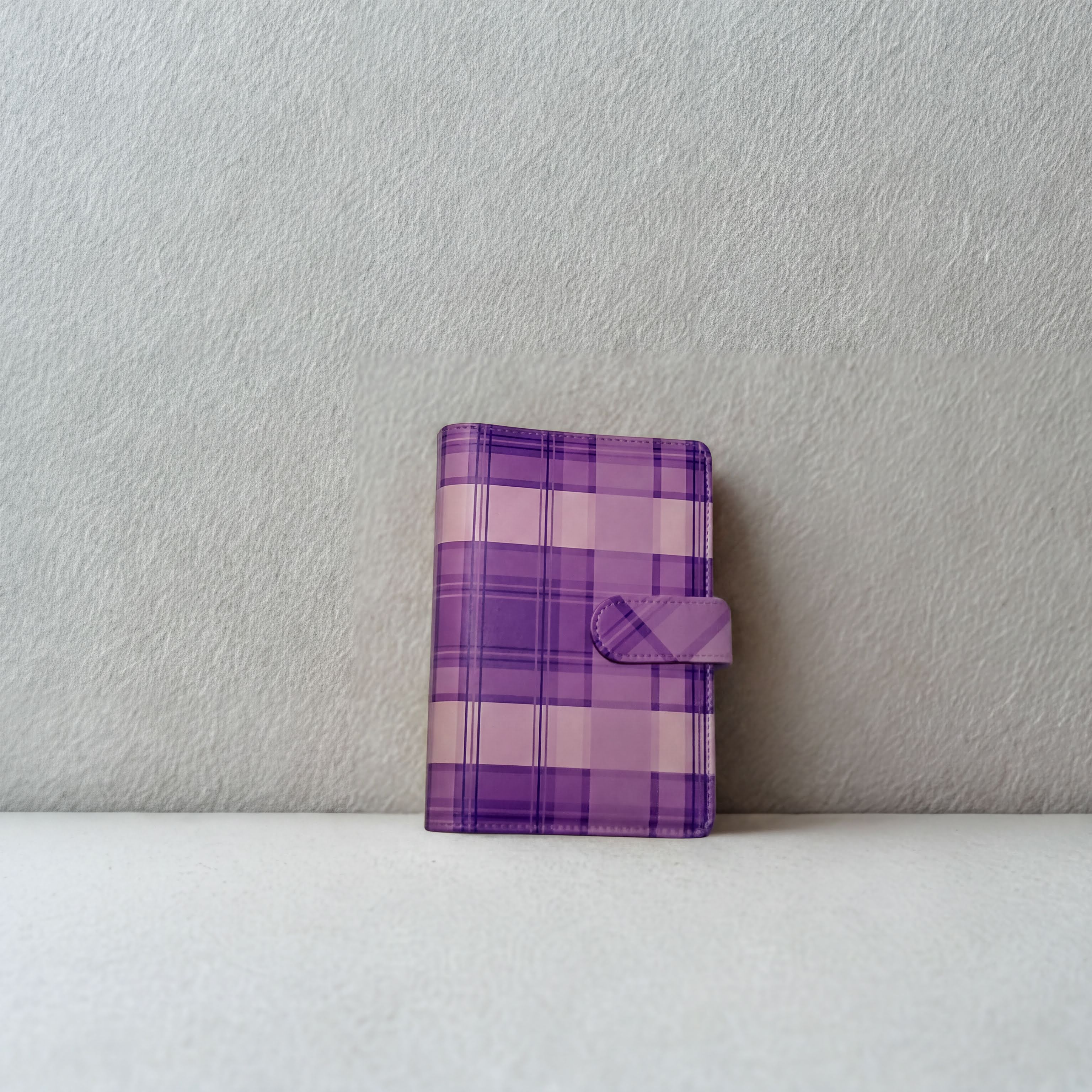 Purple plaid notebook with snap closure on white surface